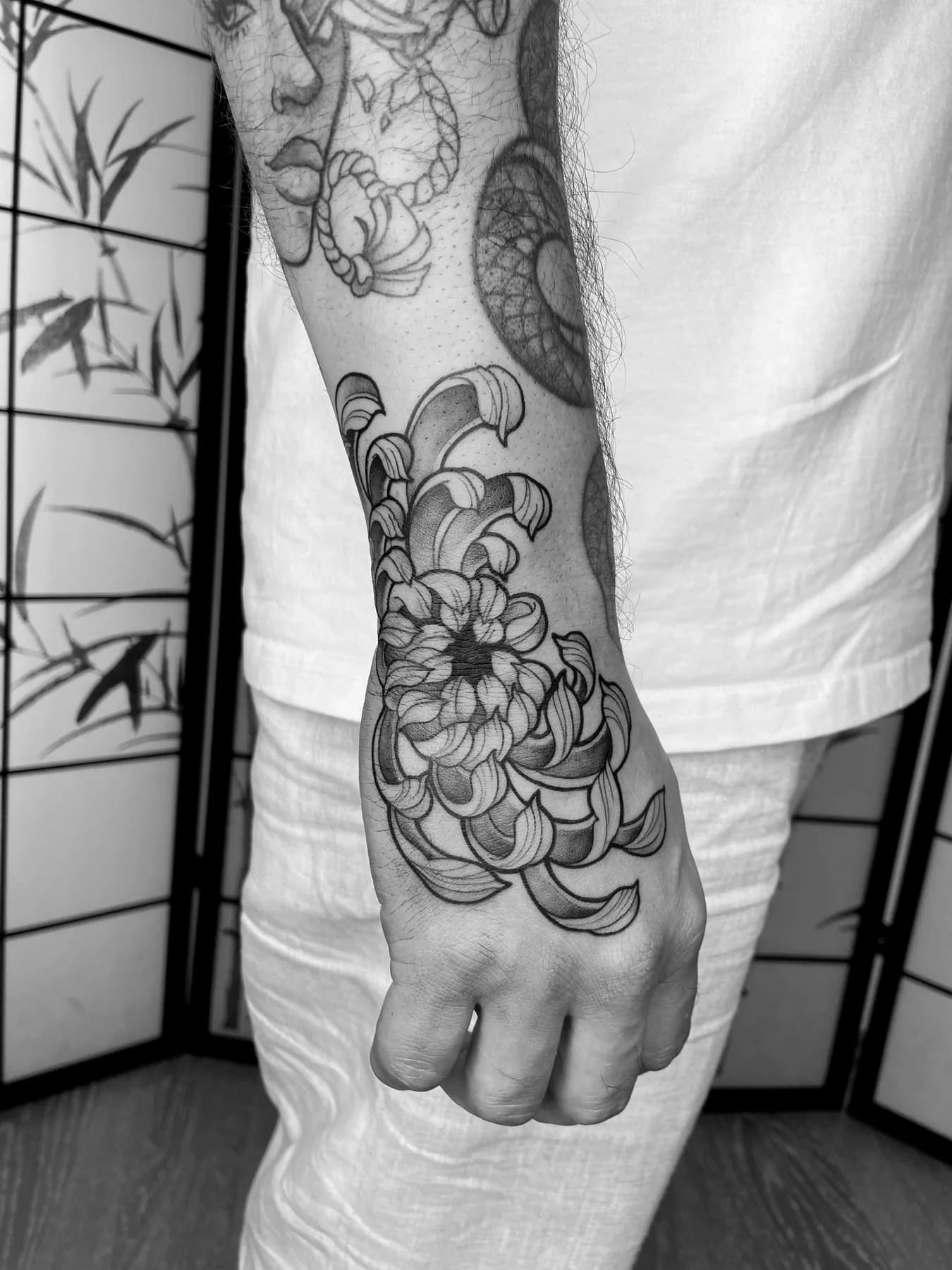 Große Blüten und ein Hamsa-Ornament auf Unterarm und Handrücken